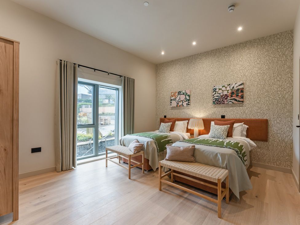 A bedroom with two beds, a window, and wall art at tbc in St. Ives