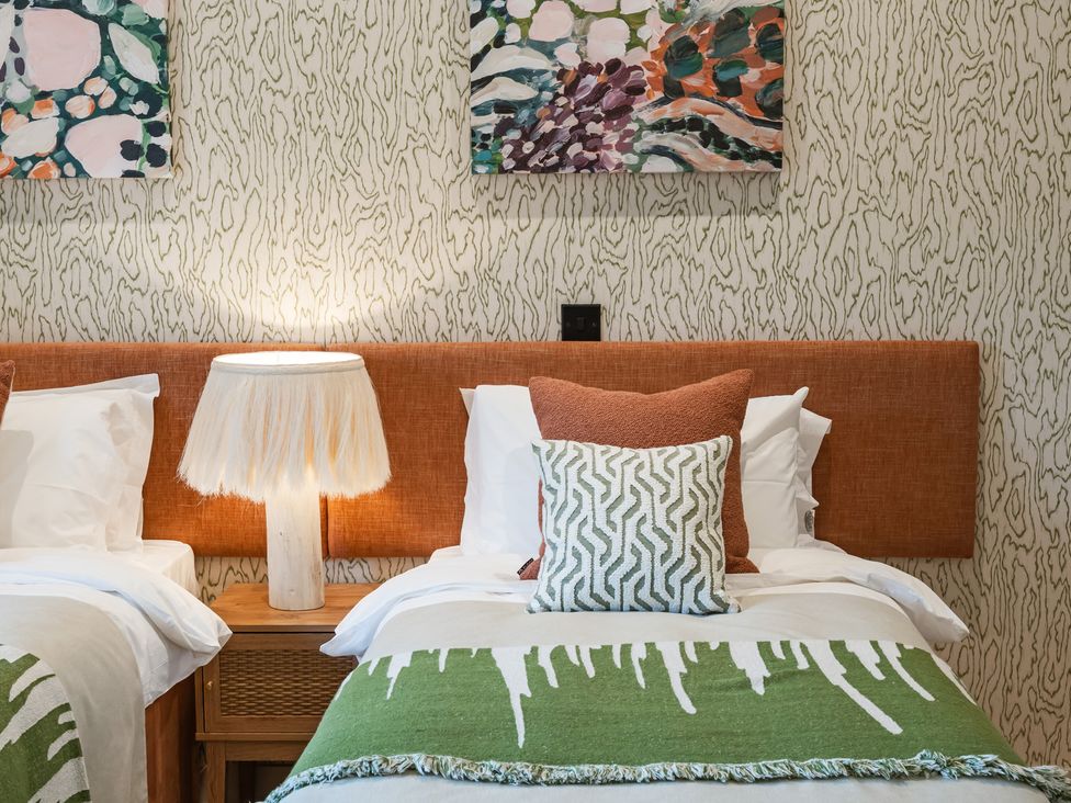 A bedroom with two beds and a bedside lamp at The Old Barn in St. Ives