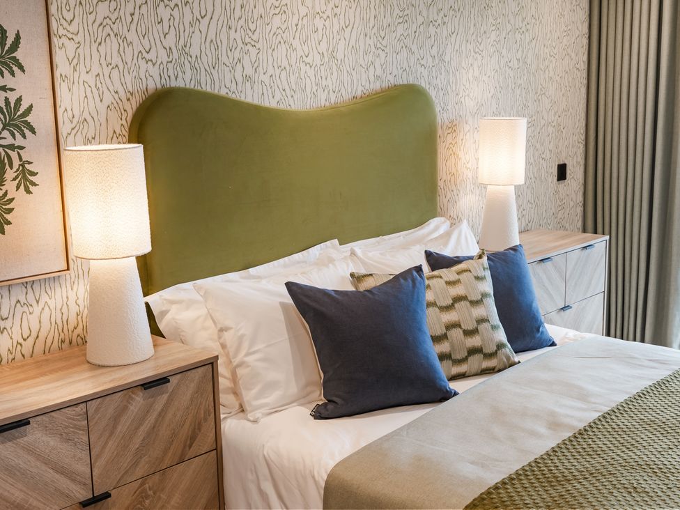 A bedroom with a green headboard and bedside lamps at The Old Barn in St. Ives