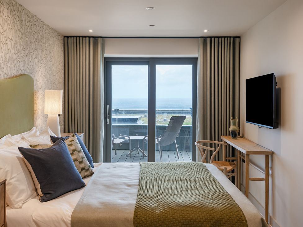 A bedroom with a bed, television, and sliding door at tbc in St. Ives