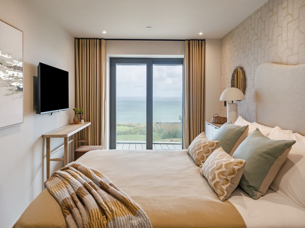 A bedroom with a bed and window overlooking the sea at The Old Barn in St. Ives