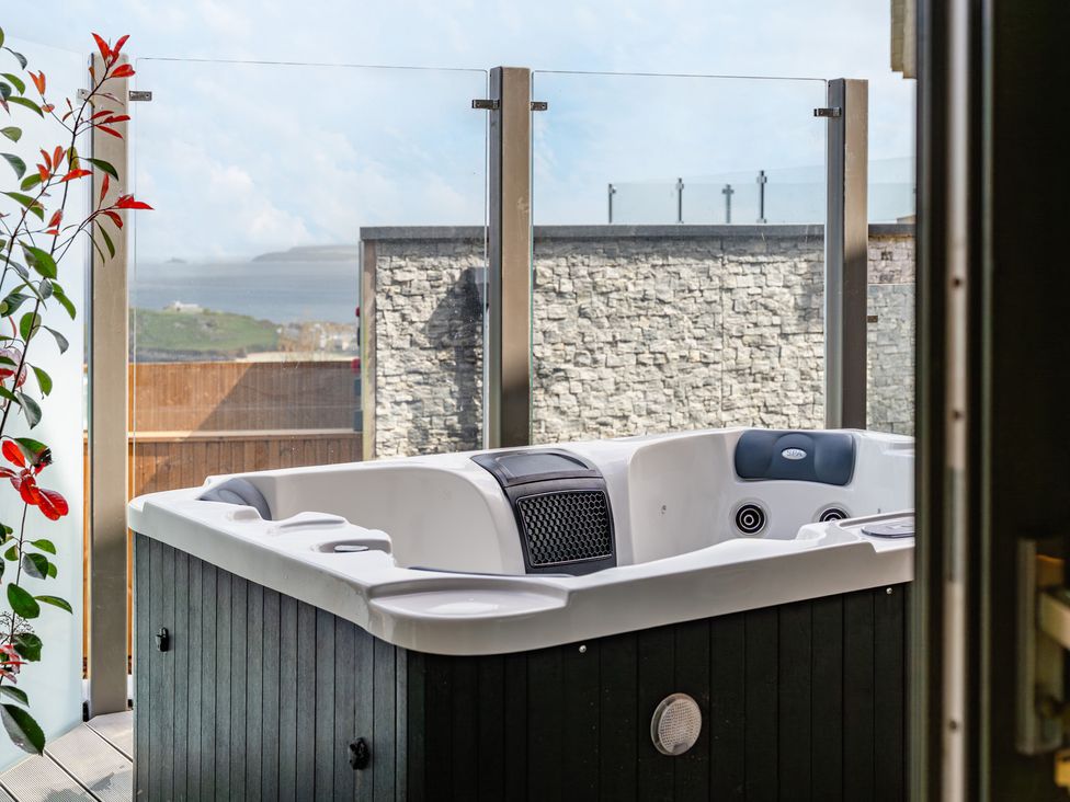 An outdoor area with a hot tub and glass railing at tbc in St. Ives