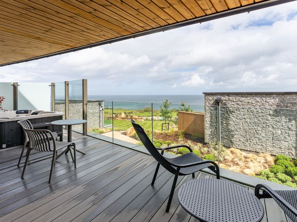 An outdoor patio with chairs and table overlooking the ocean at tbc in St. Ives