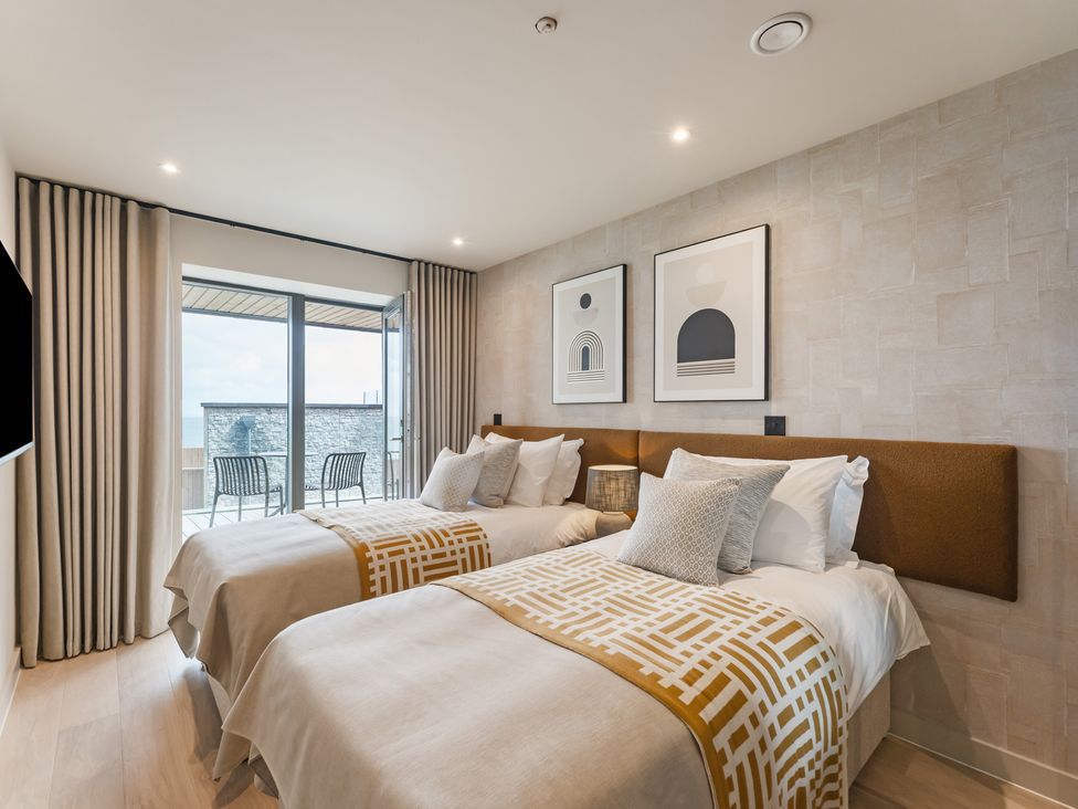 A bedroom with two beds and a sliding door at tbc in St. Ives