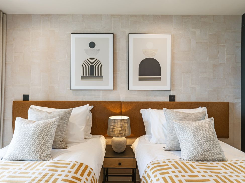A bedroom with twin beds and framed art at tbc St. Ives