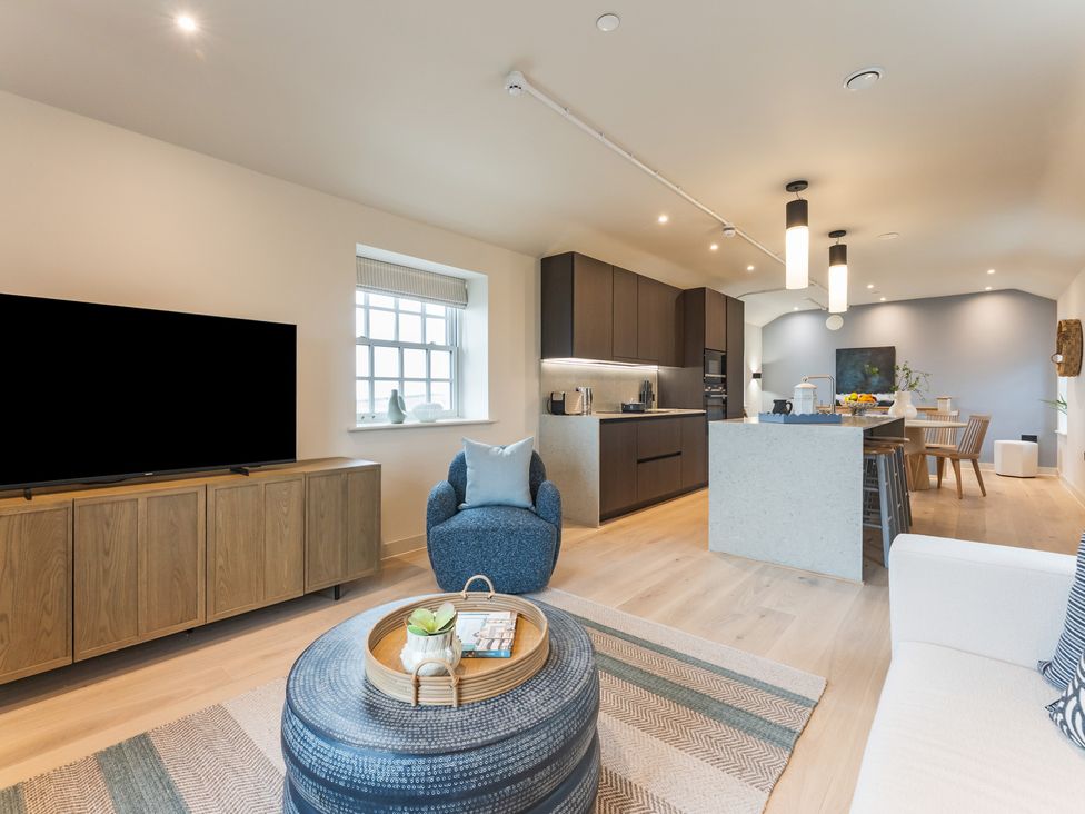 A living room with a tv, sofa and kitchen area at tbc in St. Ives