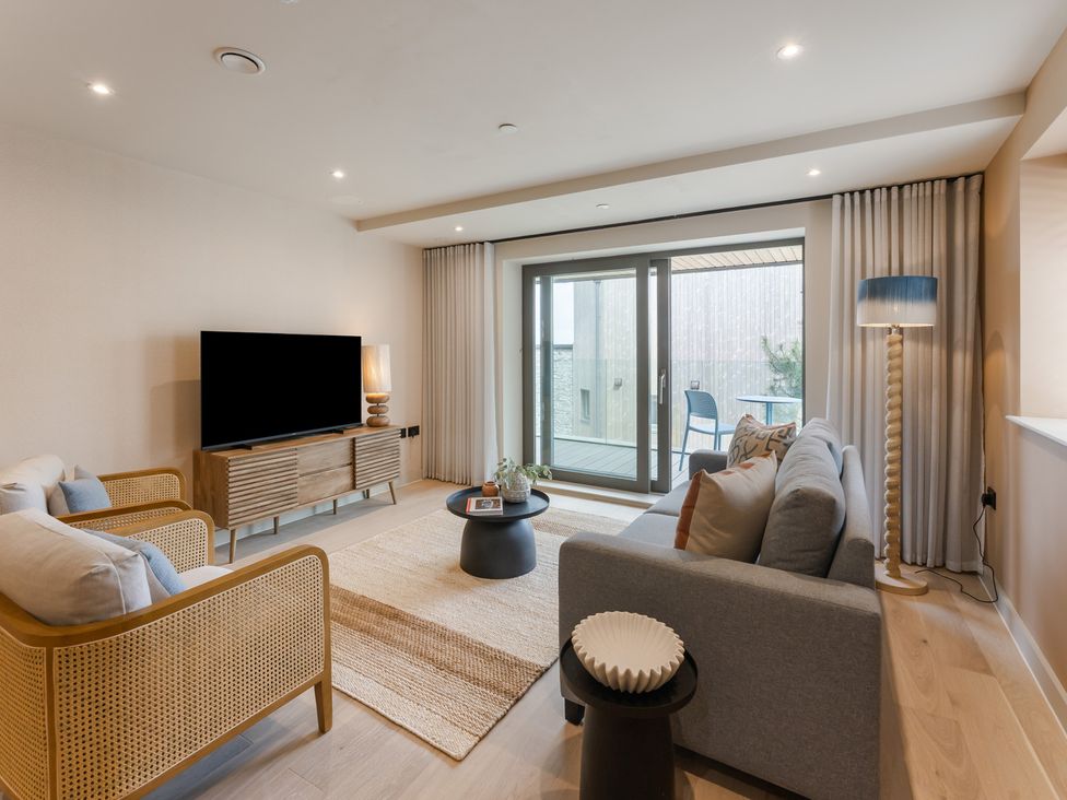 A living room with a television, sofa, and balcony access at tbc in St. Ives