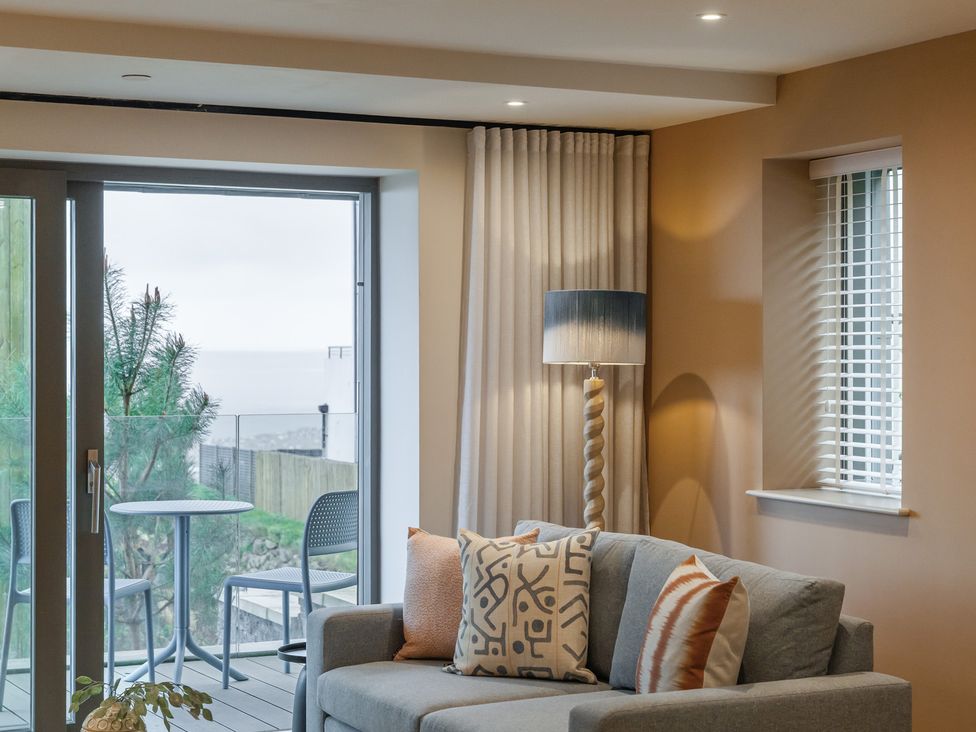 A living room with a sofa and table by a window at tbc in St. Ives