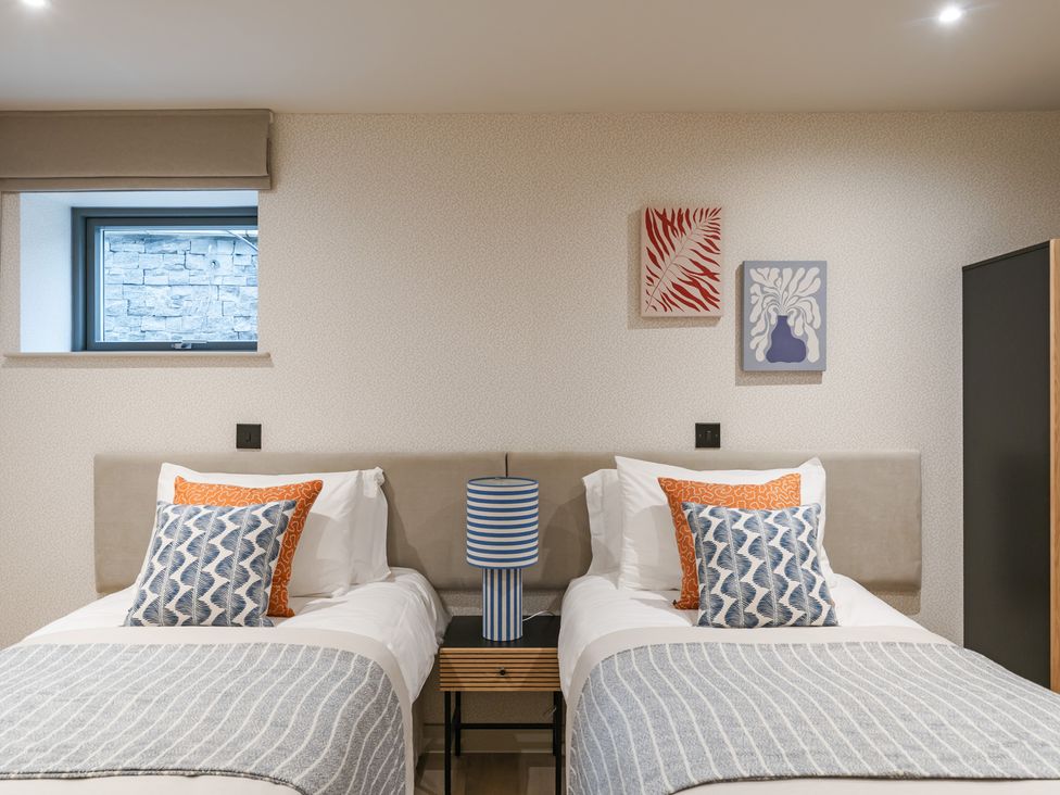 A bedroom with two beds and paintings at tbc in St. Ives