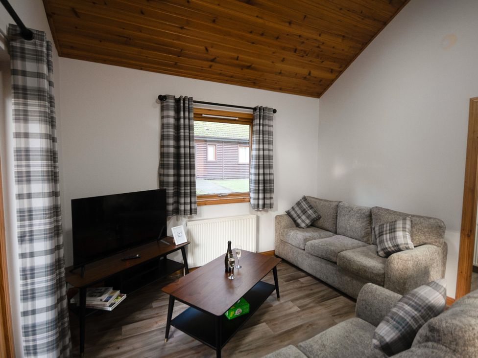 A living room with a sofa and television at Sidlaw Spa (Pet) Fowlis near Dundee