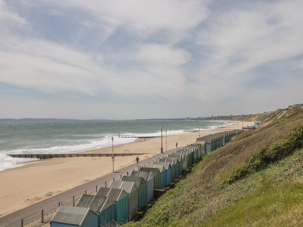 A beach with beach huts and waves at 7 Blue Water in Bournemouth