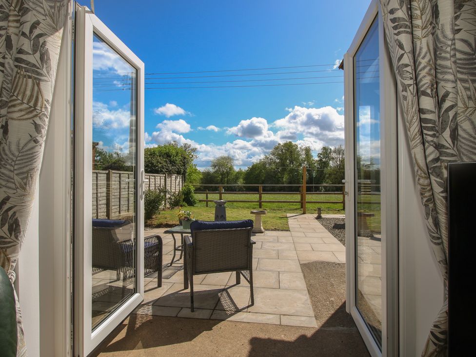 A patio area with chairs and a table overlooking a garden at Onny Views in Craven Arms