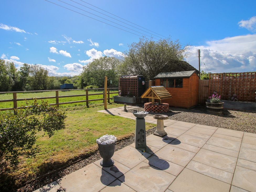 A garden with a shed and a bird feeder at Onny Views Craven Arms