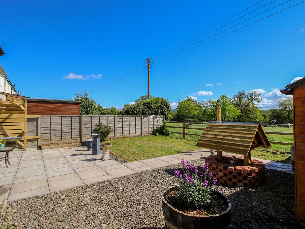 A garden with a patio and flower pot at Onny Views in Craven Arms