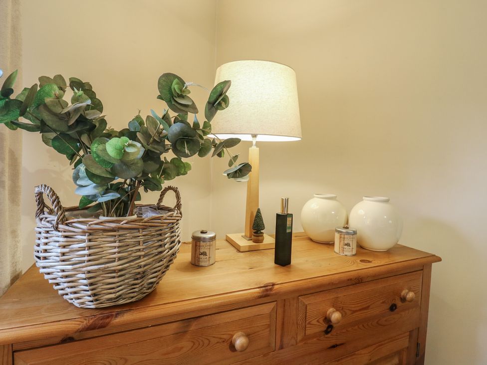 A living room with a lamp and decor on a dresser at Barclay Cottage in Biddenden