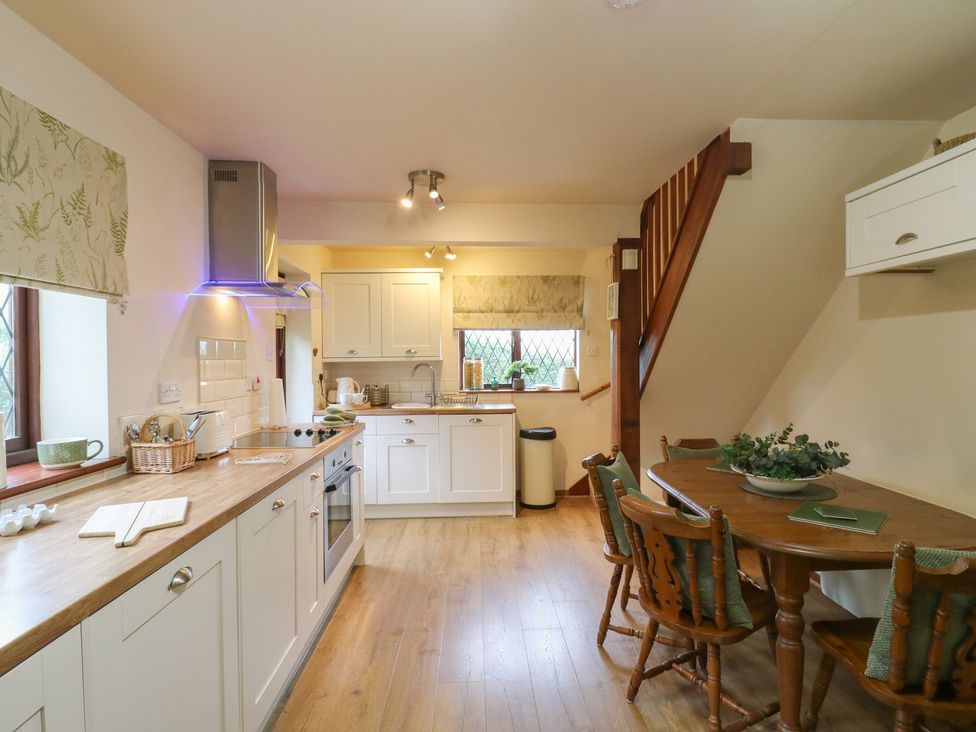 A kitchen with cabinets, a table, and chairs at Barclay Cottage in Biddenden
