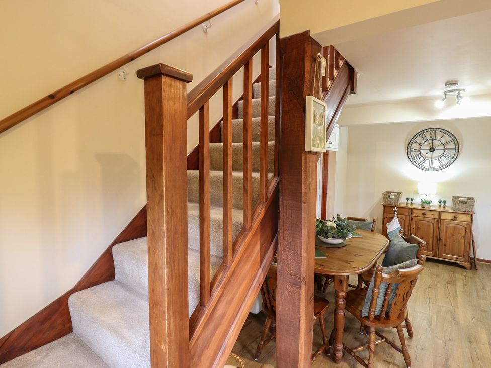 A staircase and dining area with a clock at Barclay Cottage Biddenden