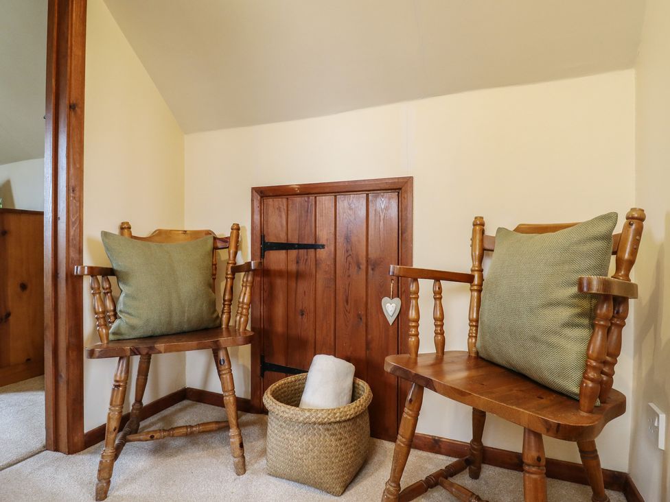 A snug with two wooden chairs and a basket at Barclay Cottage in Biddenden
