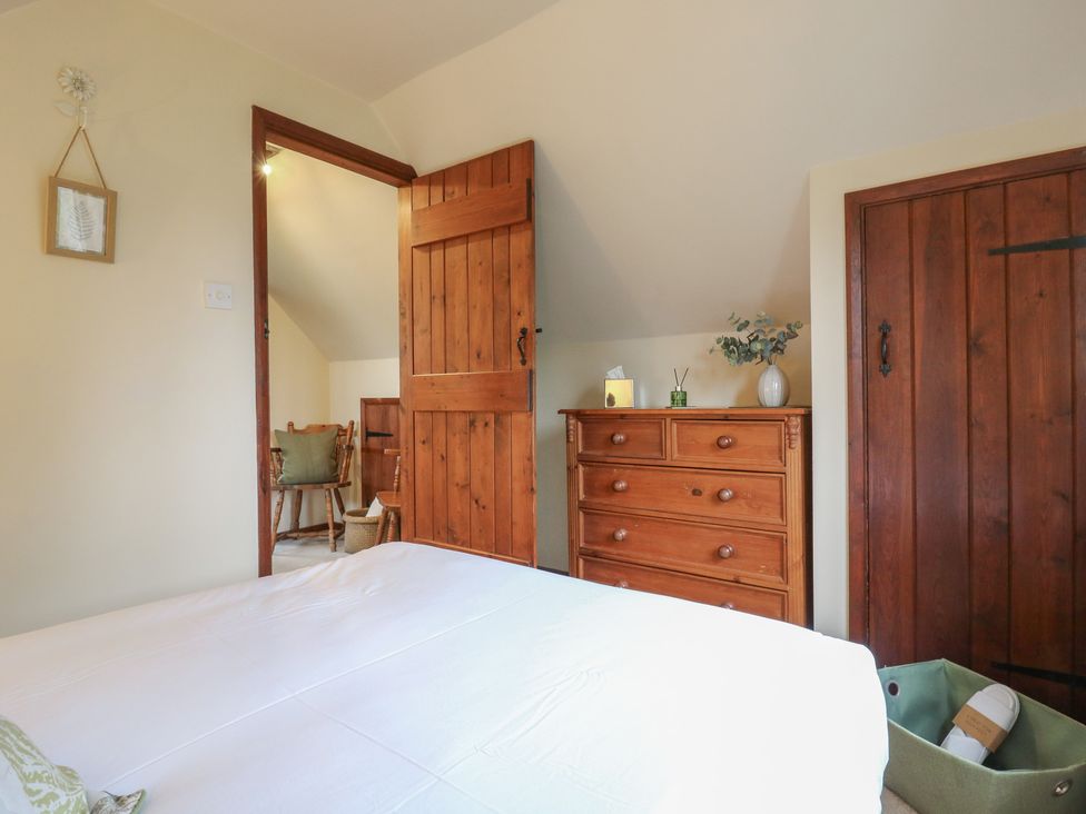A bedroom with a bed and wooden furniture at Barclay Cottage in Biddenden