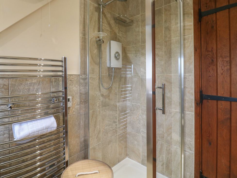 A shower with towel rail and wooden door at Barclay Cottage in Biddenden