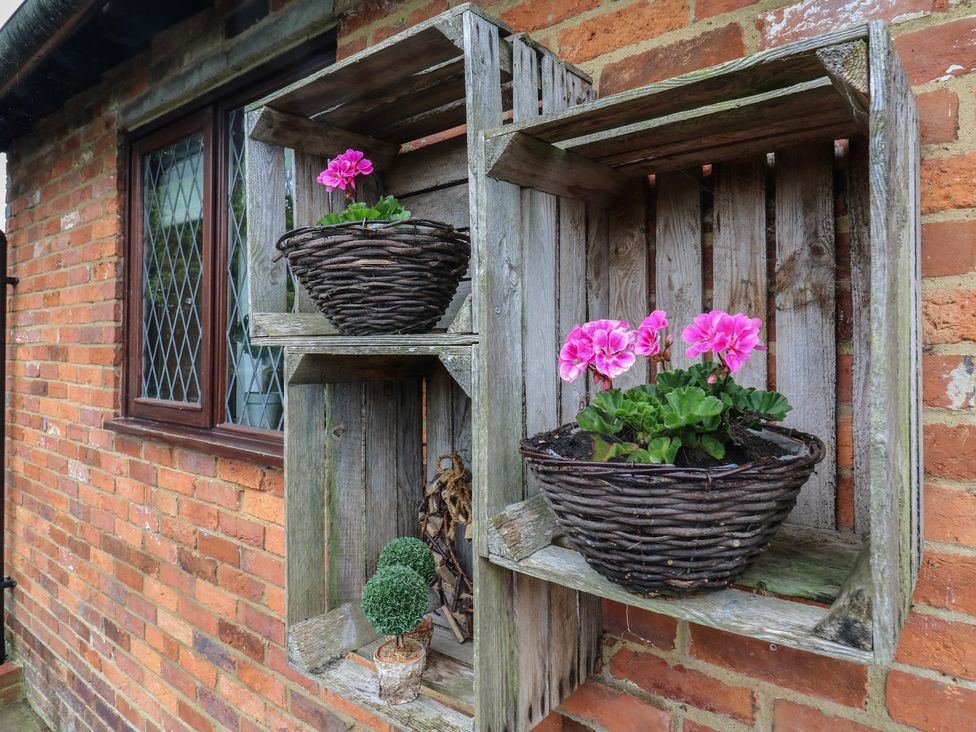 A wall mounted wooden planter with flowers at Barclay Cottage in Biddenden