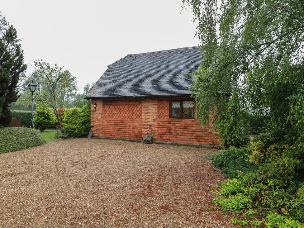 A house with a gravel driveway and trees at Barclay Cottage in Biddenden