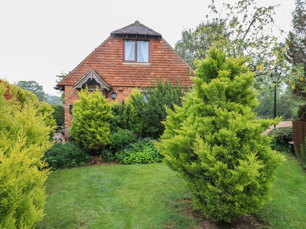 A house surrounded by trees and hedges at Barclay Cottage in Biddenden