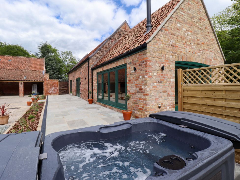 A hot tub on a paved patio at Bobblehat Barn in Alford