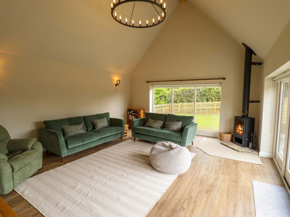 A living room with sofas and a wood stove at Bobblehat Barn in Alford