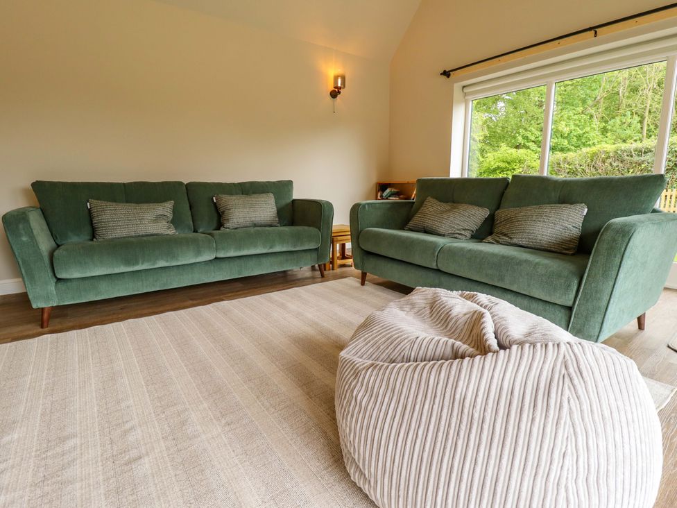 A living room with green sofas and a bean bag at Bobblehat Barn in Alford