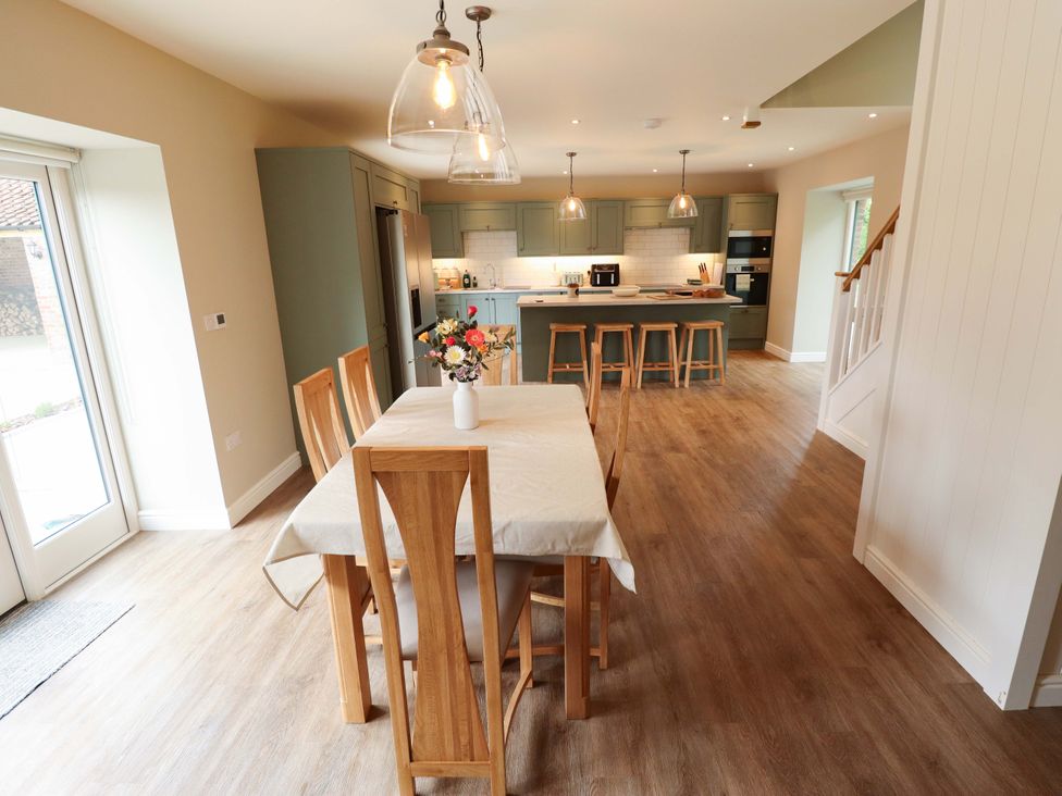 A kitchen with a dining table and flower vase at Bobblehat Barn Alford