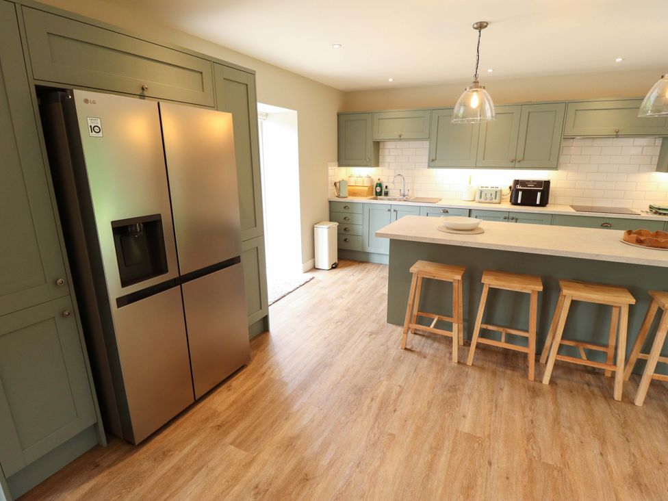 A kitchen with a refrigerator and stools in Bobblehat Barn Alford