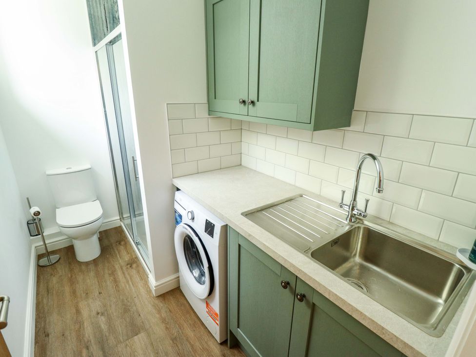 A laundry room with a washing machine and sink at Bobblehat Barn in Alford