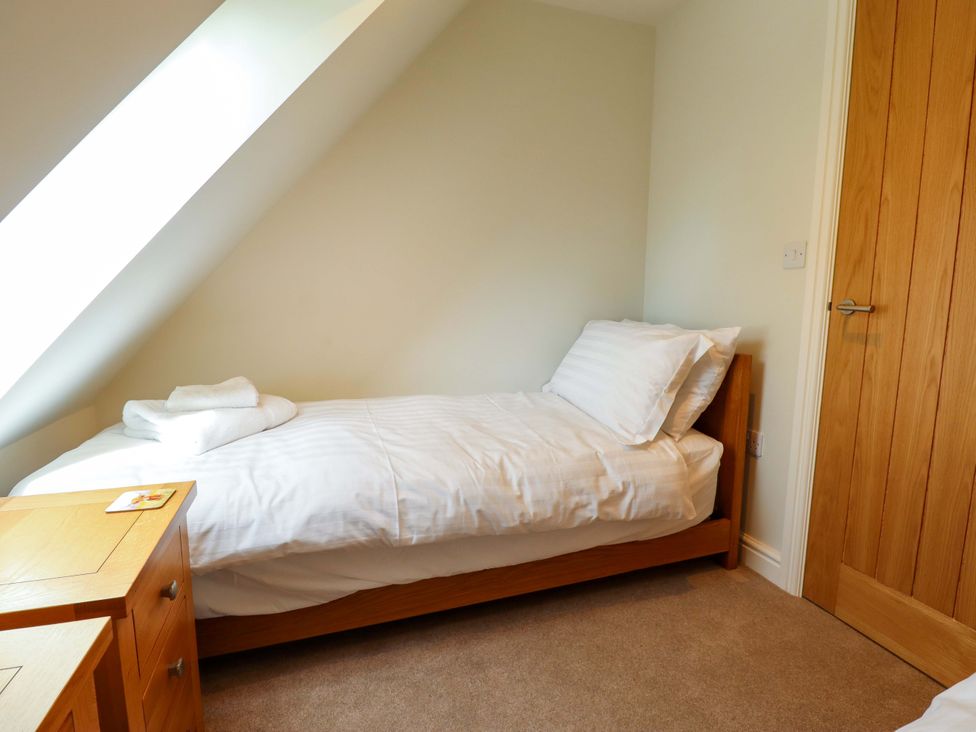 A bedroom with a bed and wooden cabinet at Bobblehat Barn in Alford