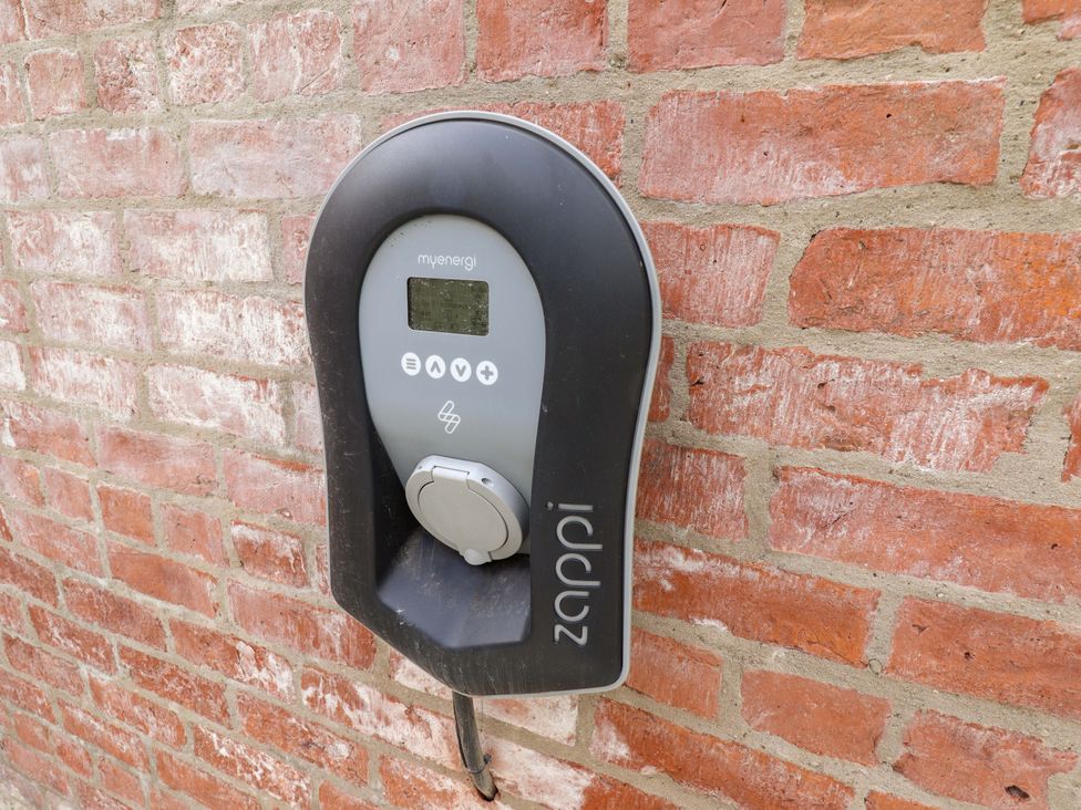 An electric vehicle charger mounted on a brick wall at Bobblehat Barn in Alford