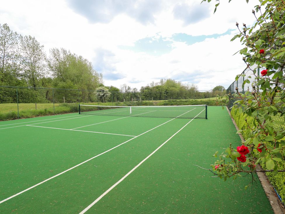 A tennis court with a net and flowers at Bobblehat Barn in Alford