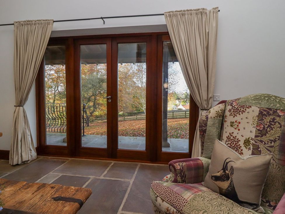 A living room with a view of trees through double doors at Sandy Gate in Knaresborough