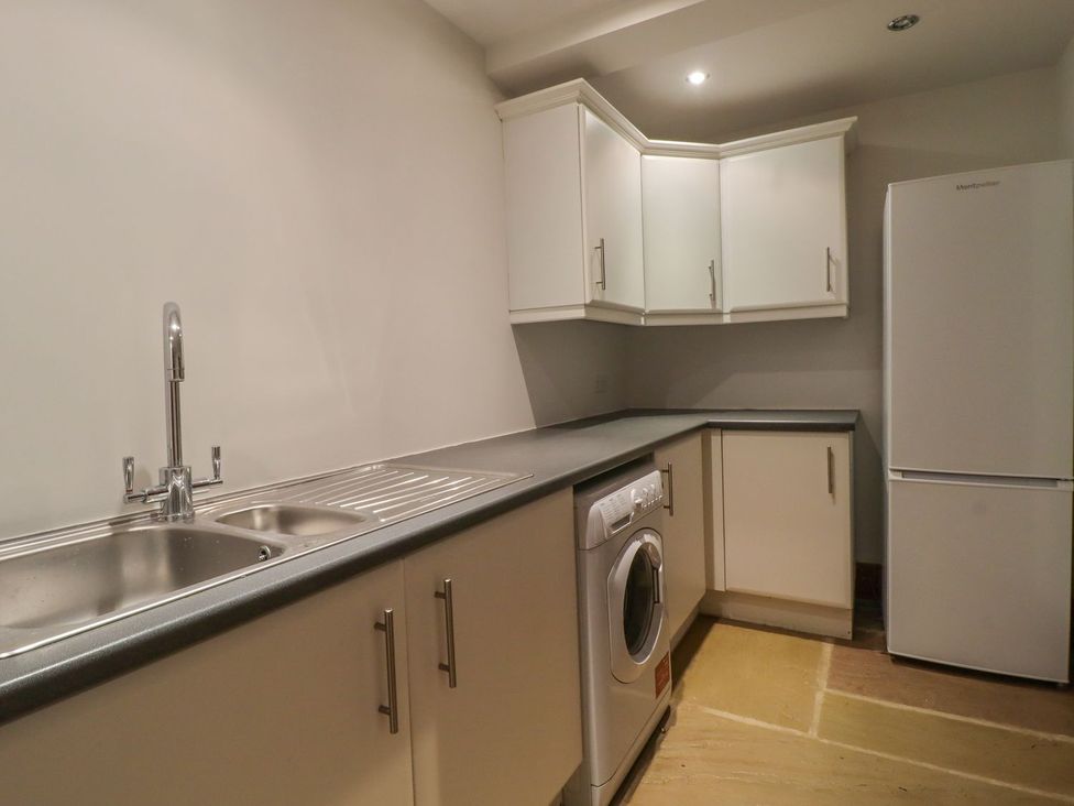A kitchen with a sink, washing machine, and refrigerator at Sandy Gate in Knaresborough