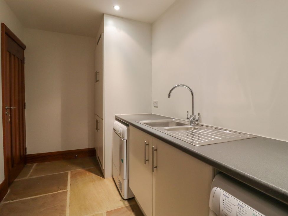 A laundry room with a sink and cabinets at Sandy Gate in Knaresborough