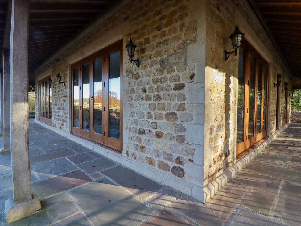 An outdoor area with stone walls and wooden doors at Sandy Gate in Knaresborough