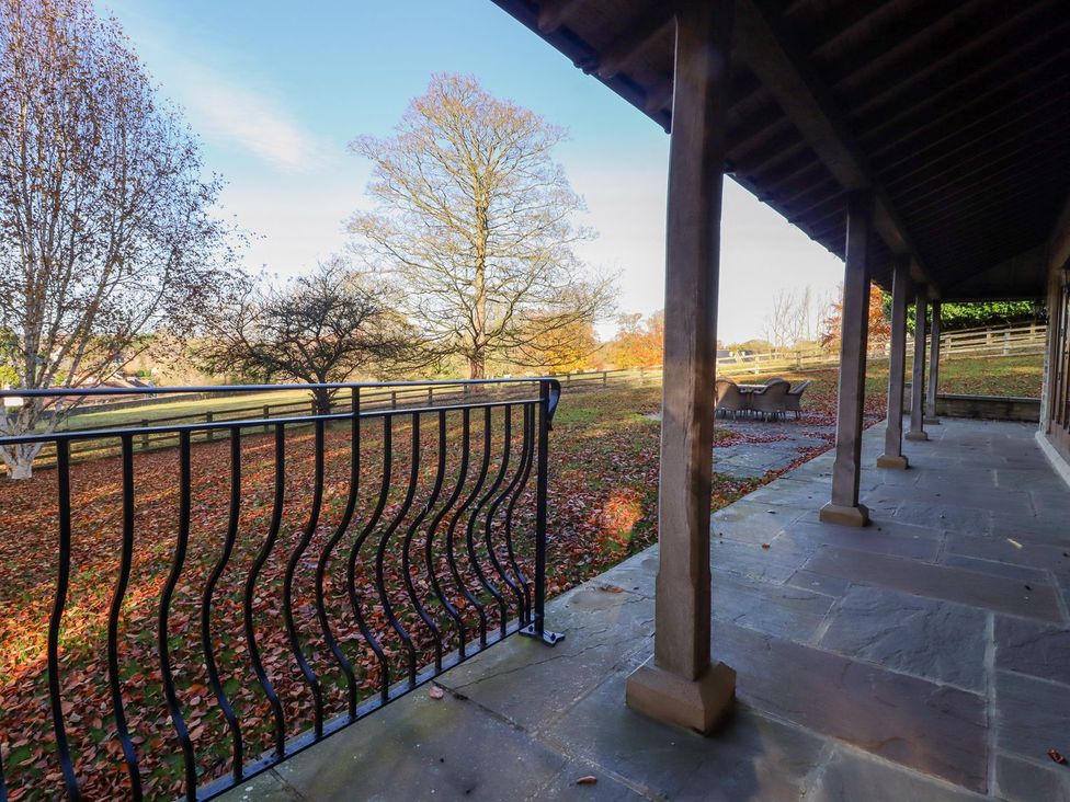 An outdoor patio area with a railing and surrounding trees at Sandy Gate Knaresborough