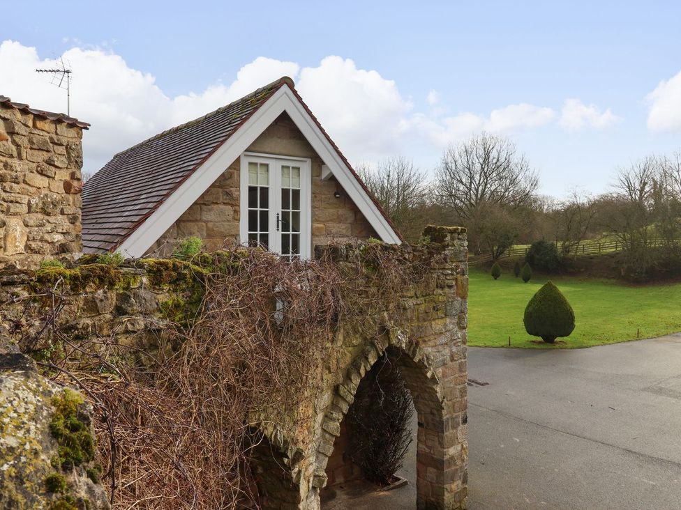 A house with a stone wall and windows in the garden at The Bothy in Knaresborough