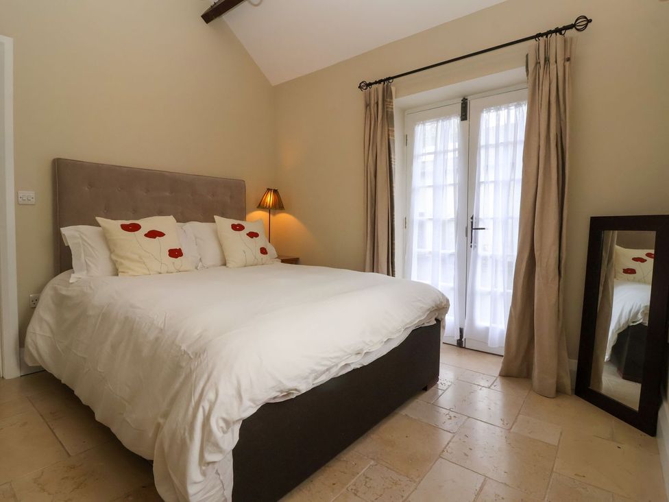 A bedroom with a bed and mirror at The Bothy in Knaresborough
