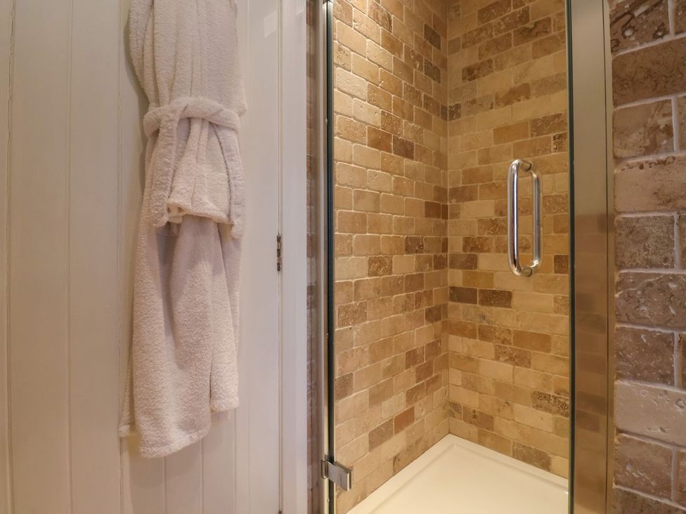 A shower with tiled walls and a towel hanging in the bathroom at The Bothy in Knaresborough