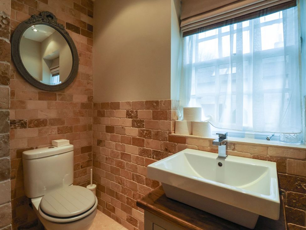 A bathroom with a toilet, sink, and mirror at The Bothy in Knaresborough
