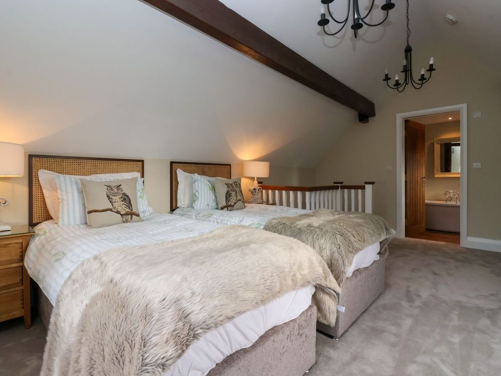 A bedroom with two beds and a doorway leading to a bathroom at The Bothy in Knaresborough