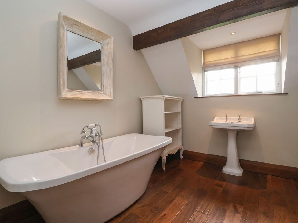 A bathroom with a bathtub, sink, and mirror at The Bothy in Knaresborough