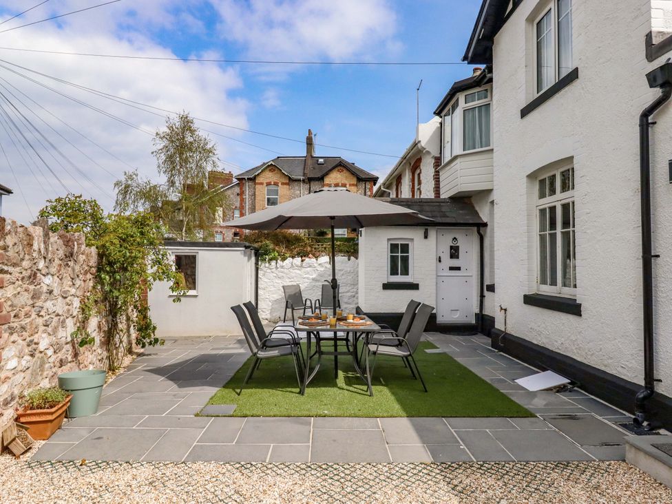 A garden with a table and chairs under an umbrella at Kents Cottage in Torquay