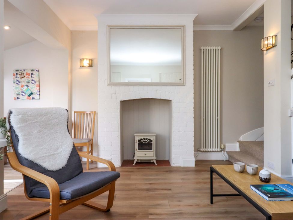A living room with an armchair and a fireplace at Kents Cottage in Torquay