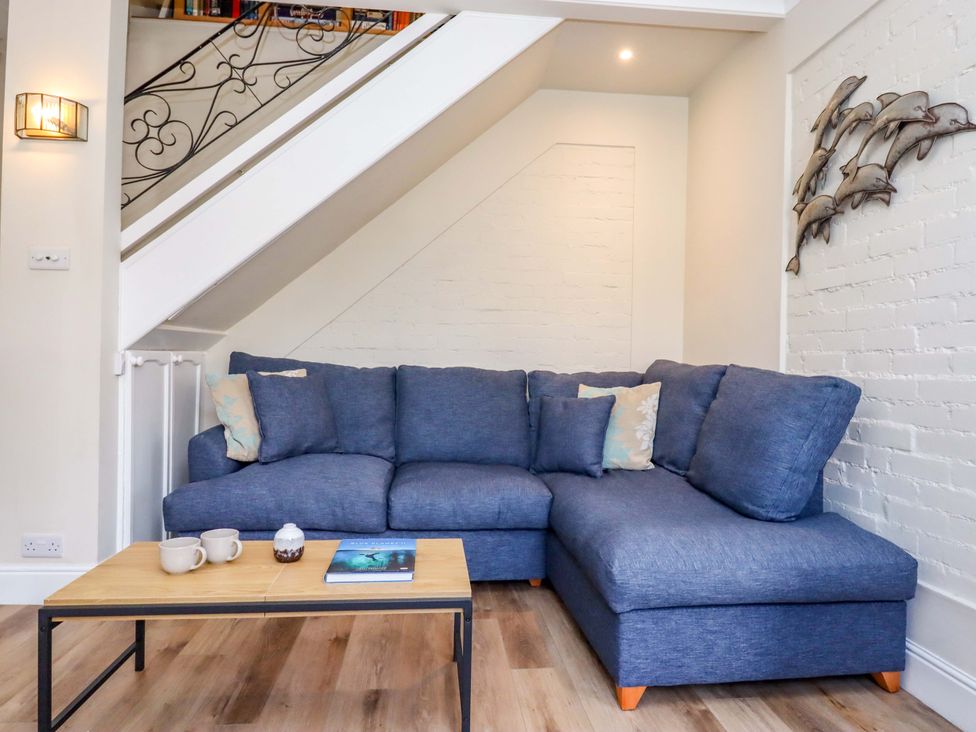 A snug with a blue sofa and coffee table at Kents Cottage in Torquay